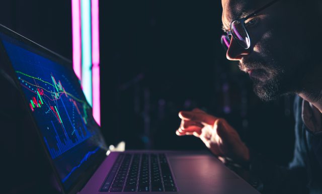 A man analyzing stock market charts, financial data on an electronic board.